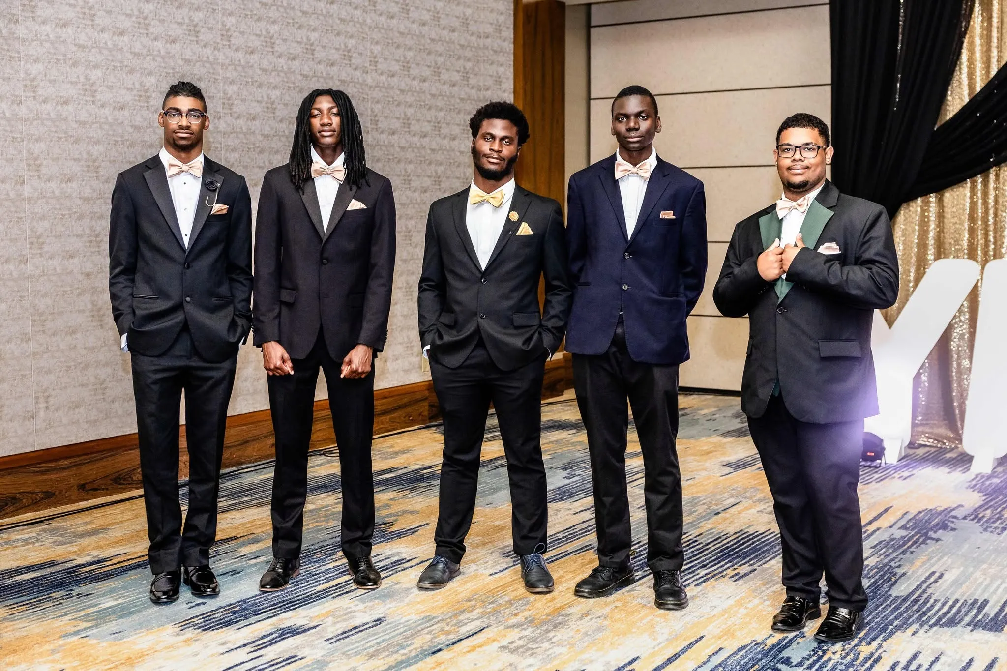 Group of young men stand together in tuxedos