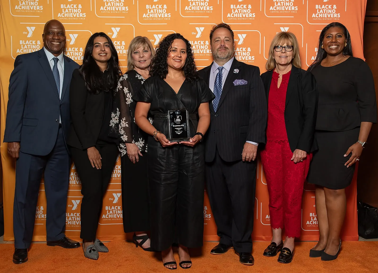 Broadview FCU Staff stand with award on orange carpet