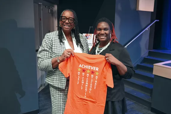 2 women holding orange shirt